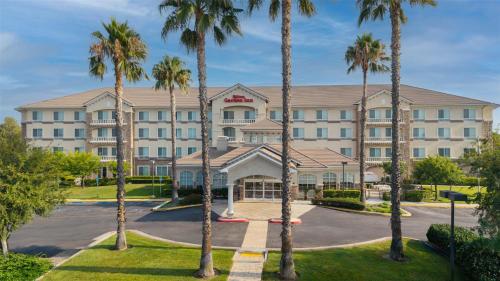 a hotel with palm trees in front of it at Hilton Garden Inn Ontario Rancho Cucamonga in Rancho Cucamonga