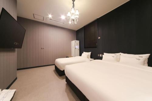 a hotel room with two beds and a chandelier at Hotel Seowa in Gimhae