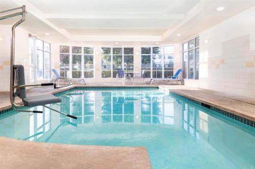 a swimming pool with blue chairs in a building at Hilton Garden Inn Ontario Rancho Cucamonga in Rancho Cucamonga