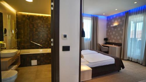a bedroom with a bed and a tub and a sink at Hotel Gallus in Sesvete