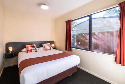 a bedroom with a bed and a large window at 298 Westside Motor Lodge in Christchurch