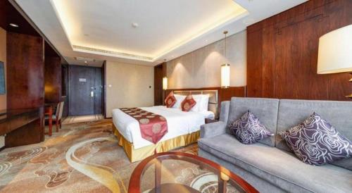 a hotel room with a bed and a couch at New Century Grand Hotel Xi'an Xizang Building in Xi'an