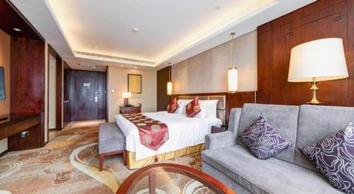 a hotel room with a bed and a couch at New Century Grand Hotel Xi'an Xizang Building in Xi'an