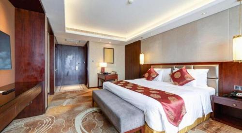 a hotel room with a large bed and a television at New Century Grand Hotel Xi'an Xizang Building in Xi'an