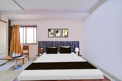 a bedroom with a large bed and a table at Super Townhouse LIG Main Road Indore in Indore