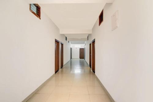 an empty hallway with white walls and tile floors at Super Collection O Madikeri City Center Near KSRTC Bus Stand Coorg Formerly Hotel Ragsys in Madikeri