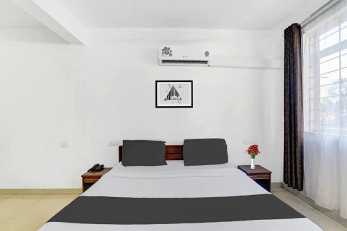 a white bedroom with a bed and a window at Super Collection O Madikeri City Center Near KSRTC Bus Stand Coorg Formerly Hotel Ragsys in Madikeri
