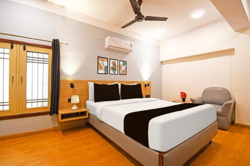 a bedroom with a large white bed and a chair at Super Townhouse Hill Cart Road Siliguri in Siliguri