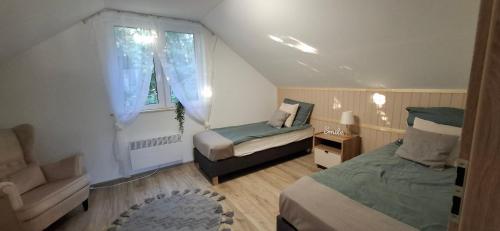 a bedroom with a bed and a chair and a window at Domek KAMA in Giżycko