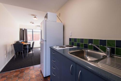 a kitchen with a sink and a refrigerator at 298 Westside Motor Lodge in Christchurch