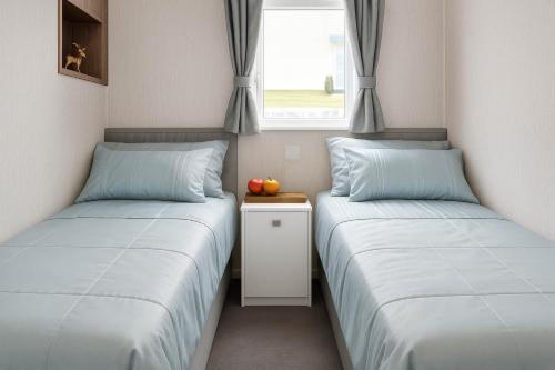 two twin beds in a room with a window at Hopton Holiday Village - Holiday Accommodation 632 in Hopton on Sea