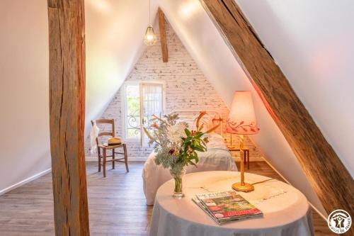 a room with a bed and a table with a lamp at Le logis du cliquet in Thibivillers