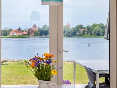 a view of a lake from a window with a vase of flowers at 8 person holiday home in Præstø in Præstø