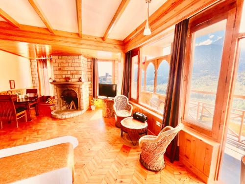 a living room with a fireplace and a tv at Hotel Valley of Vashisht - Scenic River & Mountain View Hotel in Manali in Manāli