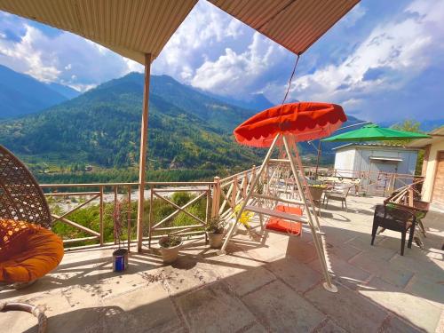 a patio with two umbrellas and a view of a mountain at Hotel Valley of Vashisht - Scenic River & Mountain View Hotel in Manali in Manāli