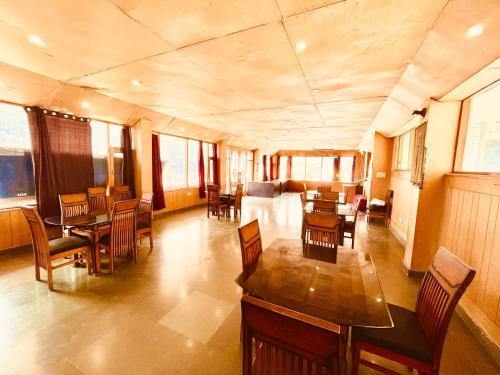 a living room with wooden tables and chairs at Hotel Valley of Vashisht - Scenic River & Mountain View Hotel in Manali in Manāli