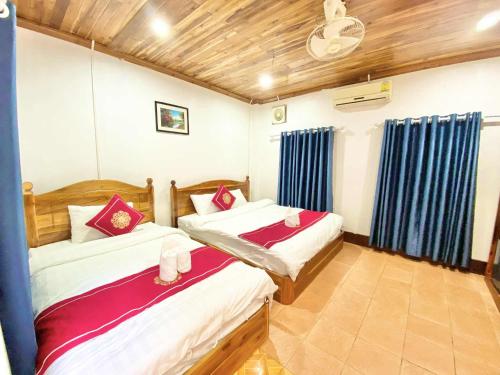 two beds in a room with blue curtains at Villa That Luang Legend in Luang Prabang