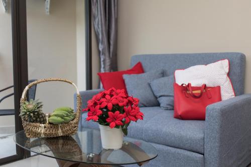 a living room with a couch and a table with red flowers at MIRA Condo 1BR Pool View NBC Nai Harn in Nai Harn Beach