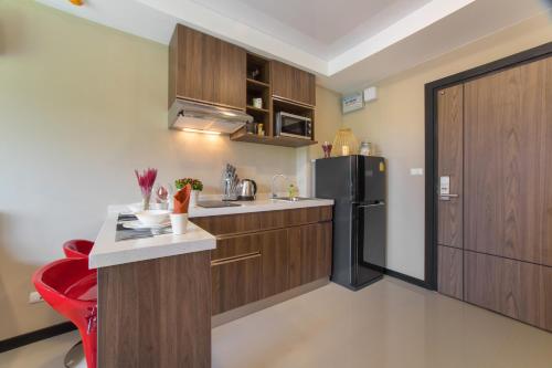 a kitchen with wooden cabinets and a black refrigerator at MIRA Condo 1BR Pool View NBC Nai Harn in Nai Harn Beach