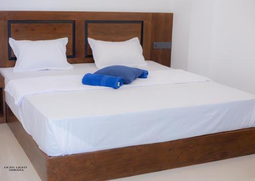 a large bed with a blue pillow on it at Ocean Light Mirissa in Mirissa