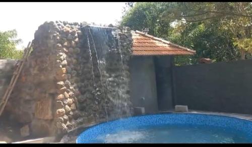 una caída de agua en una piscina con una pared de piedra en NanDha Thotram-The Central Courtyard Heritage HomeStay Yelagiri Hills, en Yelagiri