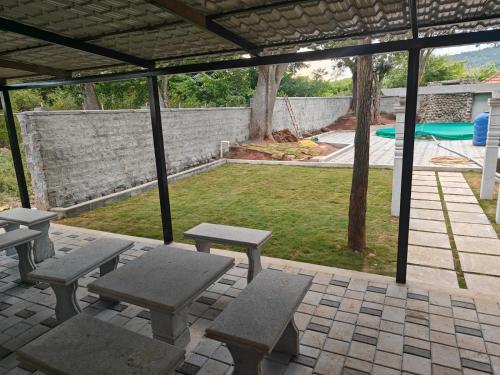 un patio con mesas de picnic y una piscina en NanDha Thotram-The Central Courtyard Heritage HomeStay Yelagiri Hills, en Yelagiri
