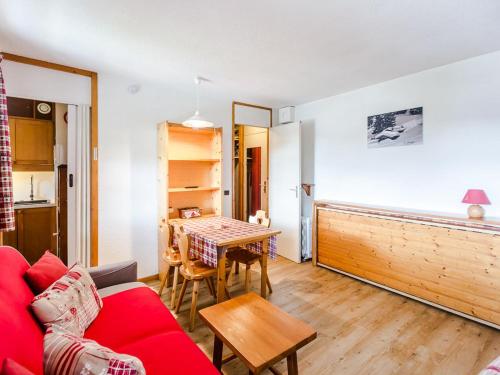 a living room with a red couch and a table at Studio rénové 3 pers, balcon sud, au pied des commerces et près des pistes - FR-1-329-4 in Bellentre