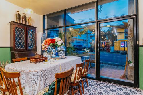 a dining room with a table with flowers on it at Nyonya Maison Boutique Hotel Phuket Old Town in Phuket Town