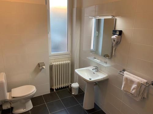 a bathroom with a sink and a toilet and a mirror at Hôtel Brasserie Le Lion d'Or in Meximieux