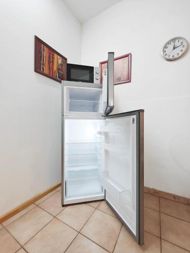 a refrigerator with its door open and a clock on the wall at Corner view 1 in Iż-Żlielaq