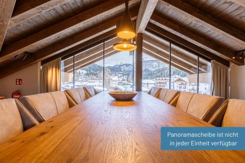 a wooden table in a room with a large window at Bergresort Zugspitze Ehrwald by ALPS RESORTS in Ehrwald