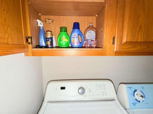 リチャードソンにあるSpacious 2BR Townhomeのボトルが置かれたキャビネットの中にある洗濯機
