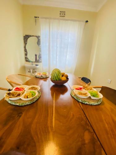 un tavolo con piatti di cibo e una ciotola di frutta di Bomani House ad Arusha
