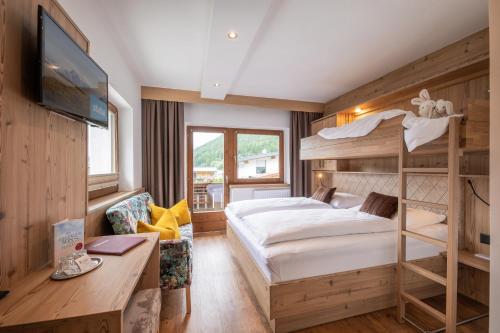 a bedroom with a bunk bed and a desk at Familien- & Vitalhotel Auenhof in Fulpmes