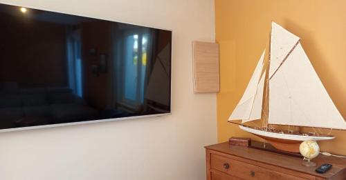 a model boat on a dresser next to a tv at Large house terrace entrance Le Touquet in Le Touquet Airport