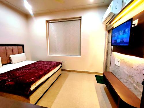 a bedroom with a bed and a window and a flat screen tv at Hotel RN Residency - Near Prem Mandir Vrindavan in Vrindāvan