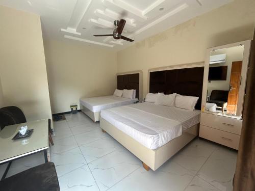 a hotel room with two beds and a mirror at Dove INN Express in Lahore