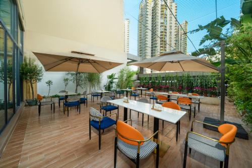 a restaurant with tables and chairs and umbrellas at Rezen Borui Hotel Guangzhou Tower Sun Yat-sen University Branch in Guangzhou