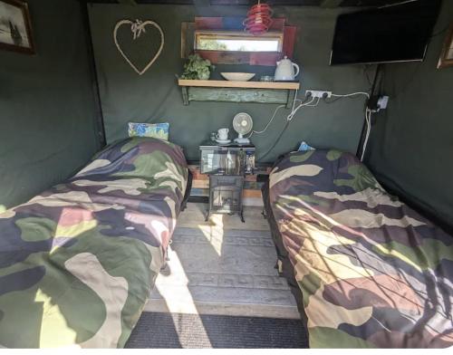 a bedroom with two beds and a table in it at The willow cabin in Bexley