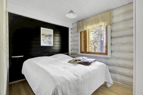 a bedroom with a white bed with a window at Villa Tundra - Valkea Homes in Pyhätunturi