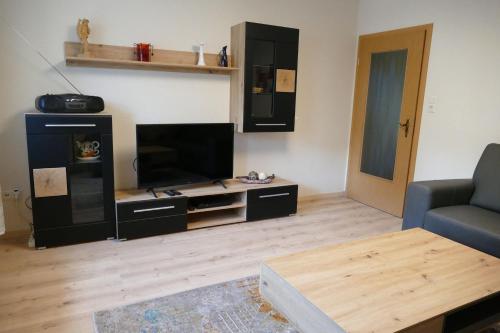 a living room with a tv and a couch and a table at Silvias Ferienwohnung - Bohlweg 43 in Wildemann