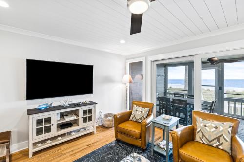 a living room with a flat screen tv and chairs at Beach Club Villa 32 - Newly Renovated! Direct Oceanfront in Isle of Palms