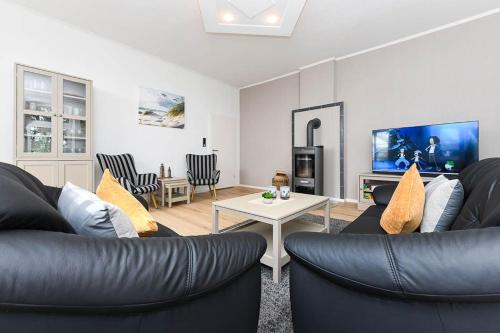 Una sala de estar con dos sofás de cuero y un televisor. en Ferienwohnung Landleben am Meer, en Bensersiel