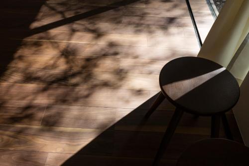 a chair in front of a window with tree shadows at Mori no Hanare in Karuizawa