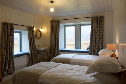 une chambre avec deux lits et deux fenêtres dans l'établissement Torran Cottage, à Achnashellach Station