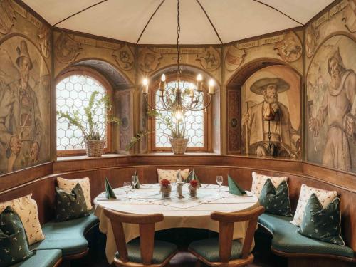 a dining room with a table and chairs and paintings at Hotel Andreas Hofer in Kufstein