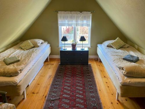 a attic room with two beds and a window at Historic Cottage In The Heart Of Österlen in Skåne-Tranås