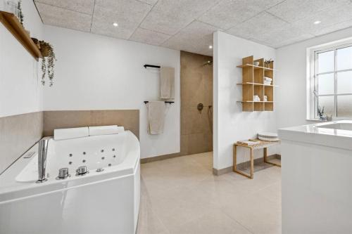 a white bathroom with a tub and a sink at Modern Family House Near Købingsmark Beach in Nordborg