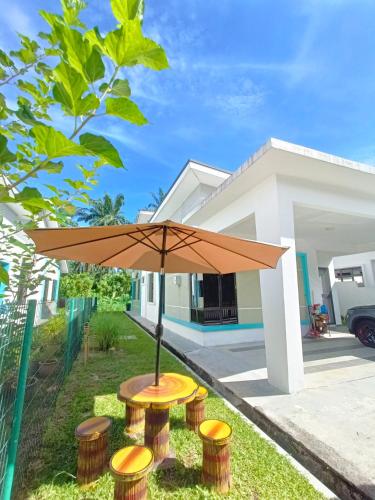 a table with an umbrella in front of a house at Zen Clan Homestay 15mins Sepang, KLIA, USIM, Nilai in Kampong Jijan Hilir