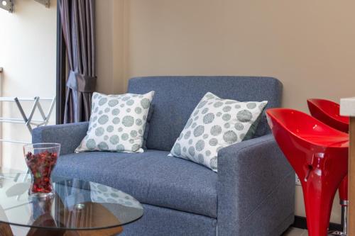 a blue couch with pillows and a glass table at SOLA Condo 1BR Tropical View NBC Nai Harn Nai in Rawai Beach